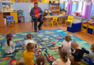 Dzieci siedzą na dywanie, pan Krzysztof czyta książkę o Kubusiu Puchatku.